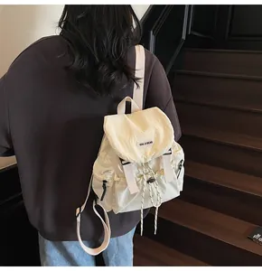 Détail d'un sac à dos en nylon crème avec fermeture à cordon et boucles à rabat élégantes