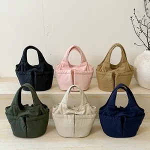 Sacs seau en nylon matelassé minimalistes en six couleurs sur des marches en marbre