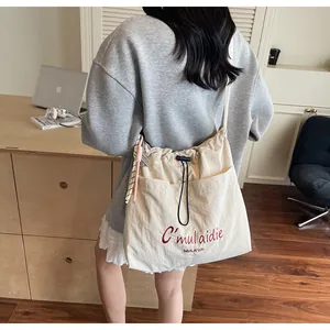 Detailansicht der cremefarbenen Segeltuchtasche mit roter Stickerei und schwarzem Kordelzug