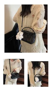 Detalle del bolso Boston negro con cuero texturizado brillante y un colgante de oso