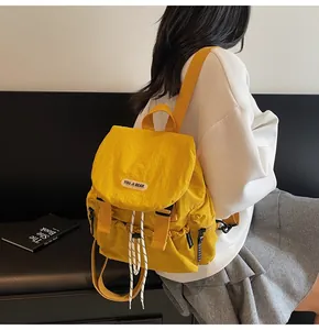 Détail du sac à dos en nylon jaune avec cordon contrastant et étiquette de marque