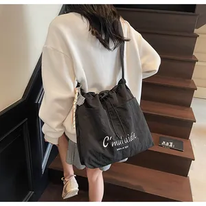Nahaufnahme der schwarzen Nylon-Tasche mit Kordelzug und weißer Logo-Stickerei