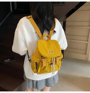 Détail d'un sac à dos en nylon jaune avec rabat et boucle porté par un mannequin