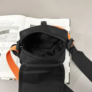 Modische schwarze Nylon-Umhängetasche mit orangefarbenem Gurt und einem Magazin