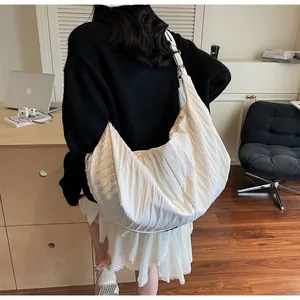Detail of large beige pleated crescent tote bag showing textured fabric and casual drape