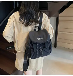 Vue arrière du sac à dos noir en nylon imperméable avec rabat et cordons rayés