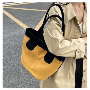 Vue détaillée d'un grand sac cabas jaune et noir porté avec un trench-coat beige élégant