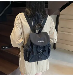 Vue arrière d'un sac à dos noir en nylon avec rabat et étiquette blanche sur un escalier