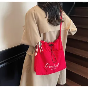 Details einer roten Kordelzug-Schultertasche mit Stickerei und gestreiftem Taschenanhänger