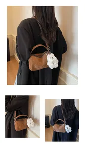 Detalle de un bolso Boston marrón brillante con un llavero de peluche de perro blanco