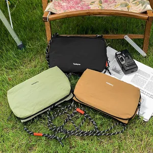 Three nylon crossbody bags in black, green and khaki on a lawn with a vintage camera