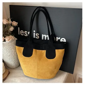 Détail du sac cabas jaune à poignées noires montrant la texture suède mate et le contraste