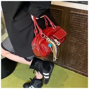 Detail of red patent leather Boston bag featuring dual front pockets and silver hardware charms