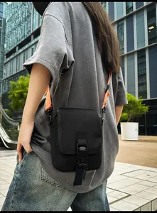 Detail der urbanen Techwear-Umhängetasche in Schwarz mit leuchtend orangefarbenem Gurt