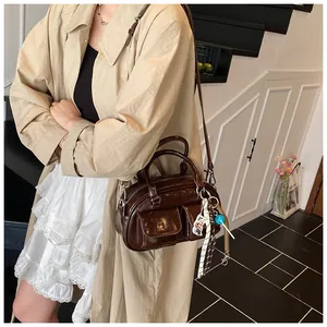 Detail of dark brown glossy bag with dual front pockets and adjustable silver hardware