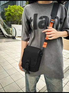 Outdoor-Aufnahme einer schwarzen taktischen Umhängetasche mit schwarz-orangefarbenem Gurt