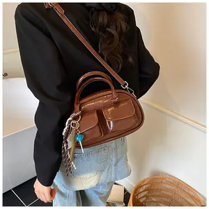 Close-up of a dark brown glossy leather bag featuring double pockets and a blue lollipop charm