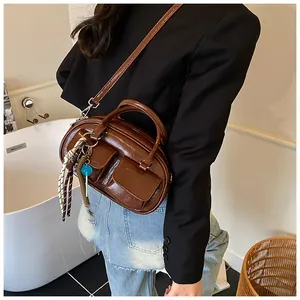 Detail of vintage dark brown bowling bag featuring glossy leather and braided lanyard charm