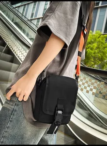 Detail der schwarzen taktischen Kuriertasche mit orangem Gurt und Kunststoffschnalle