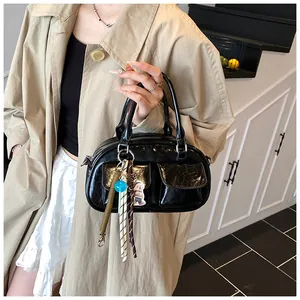 Detail of black glossy baguette bag with double flap pockets and cute plush charms