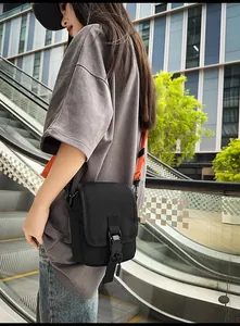 Detail einer schwarzen taktischen Kuriertasche mit verstellbarem orangefarbenem Gurt