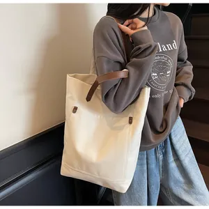 Detail of canvas tote bag with front pocket and dark brown shoulder strap for women