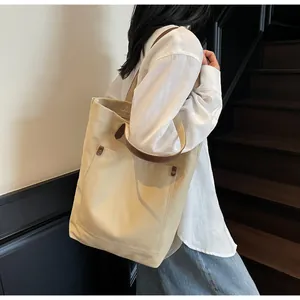Detail shot of large canvas tote bag with brown leather handles and metal rivet pocket