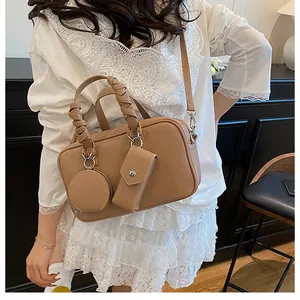 Dettaglio della borsa boston in pelle marrone chiaro con manici intrecciati e mini tasche