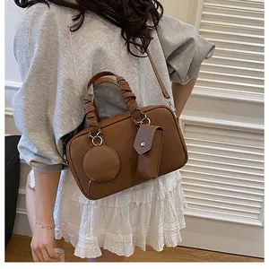 Dettaglio borsa Boston marrone in pelle martellata con manici intrecciati e bustina