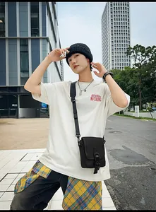 Outdoor-Streetstyle-Shot einer schwarzen Umhängetasche mit weißem Logo-T-Shirt