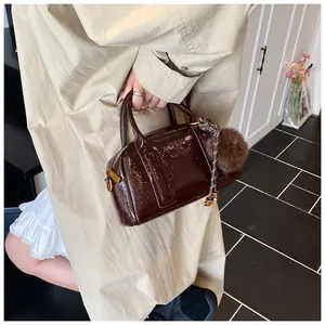 Détail du sac bowling en cuir froissé marron avec charm et lanière tissée
