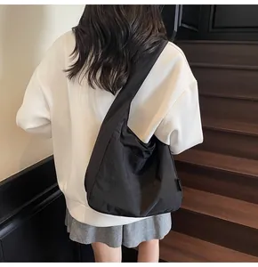 Rear view of a black minimalist Hobo tote bag styled with casual outfit on a model