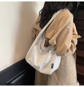 Detail of minimalist white tote bag with SHUNUO label worn with a khaki trench coat