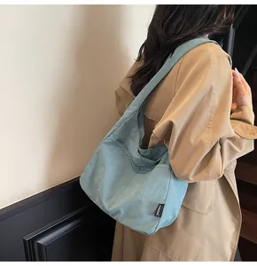Detailed view of light blue nylon tote bag showing soft texture and side logo tag
