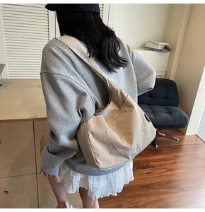 Close-up of beige textured nylon tote bag featuring side pockets and casual shoulder strap
