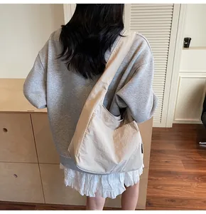 Detail of beige nylon crescent tote bag showing natural washed texture and slouchy design