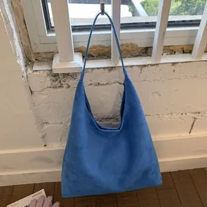Detail of bright blue suede tote bag showing large capacity and minimalist design