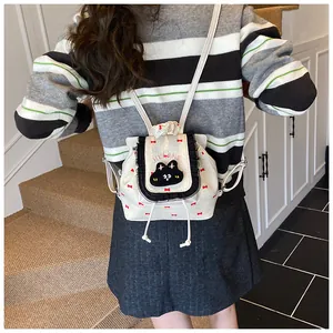 Sac à dos blanc avec imprimés nœuds rouges et broderie chat porté au dos