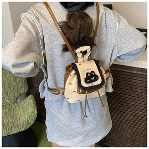Détail d'un mini sac à dos en toile avec broderie chat et motifs nœuds rouges