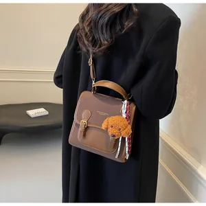 Brown vintage PU leather crossbody bag with teddy charm shown on person in a side view