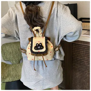 Détail du mini sac à dos beige avec bordures à volants noirs et broderie chat mignon