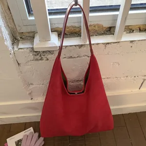 Detail of red suede hobo bag with leather shoulder strap and metallic hardware texture