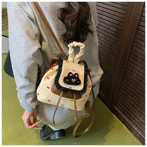 Détail d'un mini sac à dos crème avec bordure à volants et patch chat porté en bandoulière
