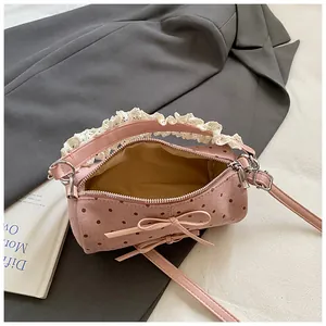 Detalle del bolso cilíndrico rosa con lunares, asas de encaje y decoración de lazo dulce