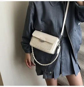 Close-up of a cream PU leather crossbody bag featuring woven texture and silver metal lock