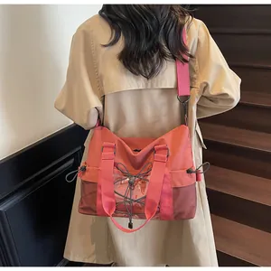 Coral pink travel tote bag worn by a model on stairs showing large capacity and nylon texture