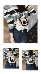 Détail d'un mini sac à dos blanc avec imprimés nœuds rouges et broderies de chat noir