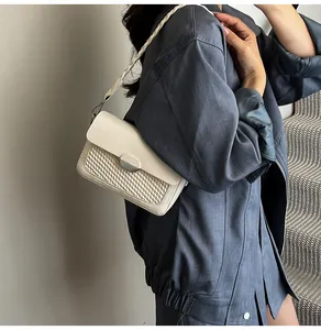 Detail of a creamy white crossbody bag featuring woven texture and a chic rope strap