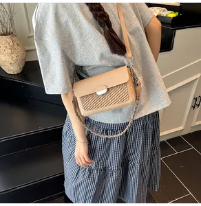 Close-up of beige square crossbody bag showing woven texture and metal buckle detail