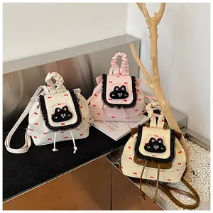 Détail de mini sacs à dos en toile avec imprimé nœud rouge et broderie chat mignon